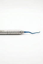 A dental pick tool with a textured silver handle and a curved blue tip, shown vertically against a plain light gray background. The brand name 'ITALACE' is printed on the handle.